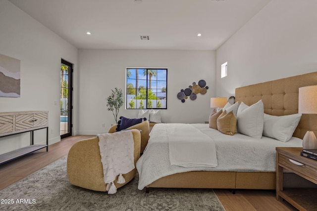 bedroom with visible vents, wood finished floors, multiple windows, and access to exterior