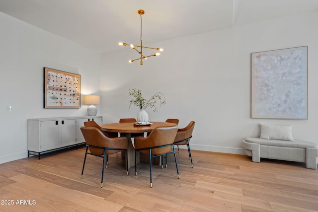 dining room featuring light wood-type flooring, baseboards, and a notable chandelier