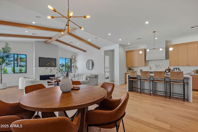 dining area featuring vaulted ceiling with beams, a chandelier, a wealth of natural light, and light wood finished floors
