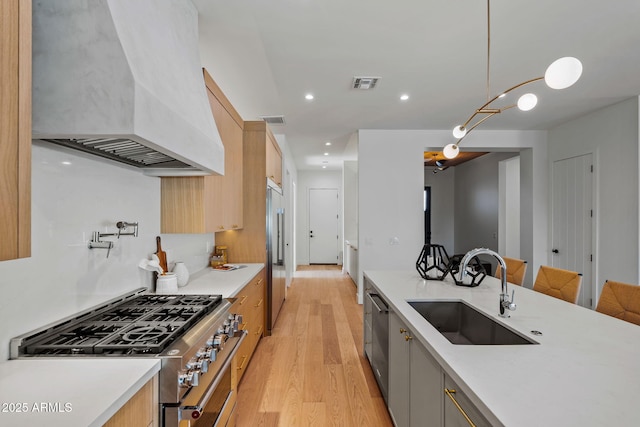 kitchen featuring a sink, custom range hood, premium appliances, visible vents, and modern cabinets