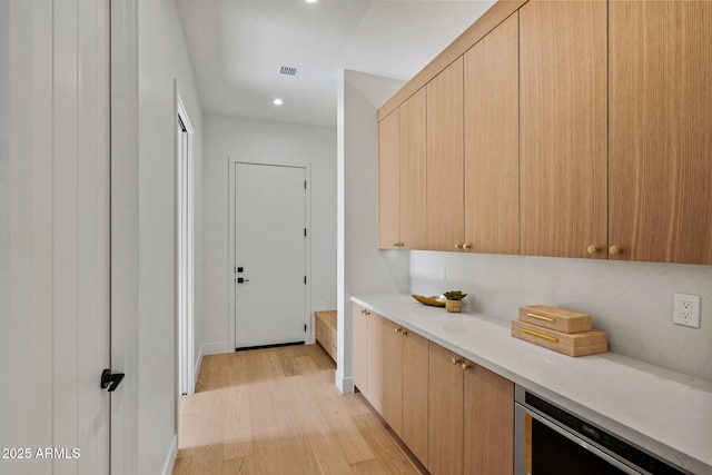 hallway featuring visible vents, baseboards, beverage cooler, recessed lighting, and light wood-style flooring