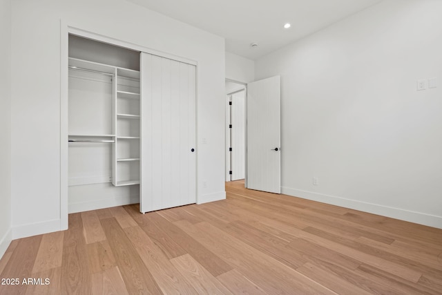 unfurnished bedroom with recessed lighting, baseboards, a closet, and light wood-style floors