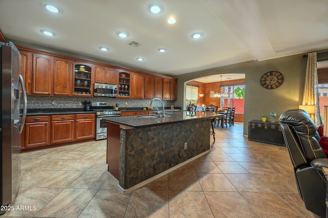 kitchen with tasteful backsplash, stainless steel appliances, sink, and a center island with sink