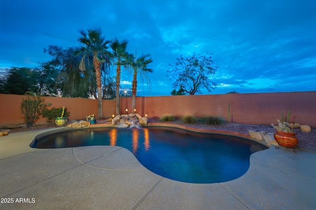 pool at dusk with a patio area