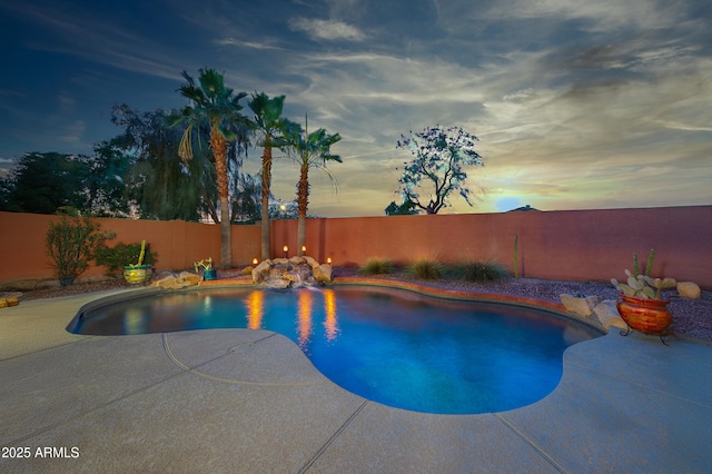 pool at dusk featuring a patio