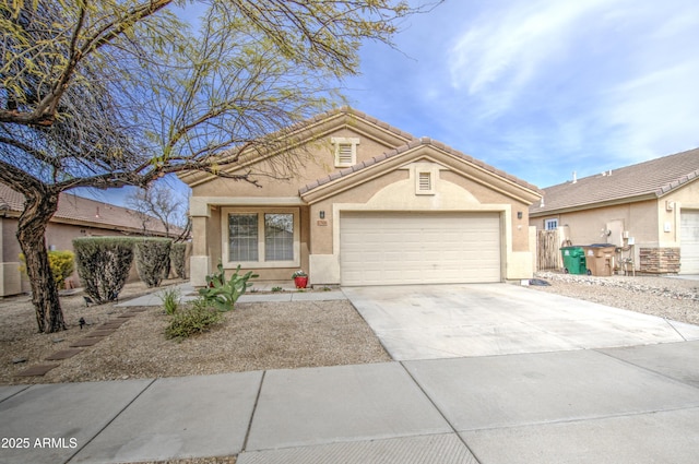 view of front of home featuring a tiled roof, an attached garage, driveway, and stucco siding