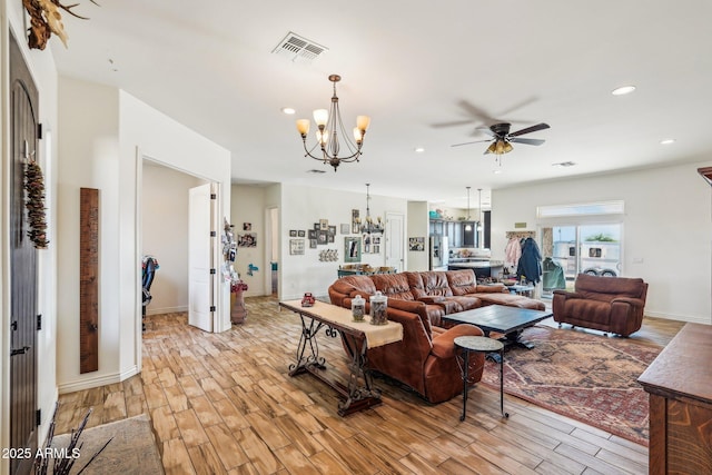 living room featuring ceiling fan with notable chandelier and light hardwood / wood-style flooring