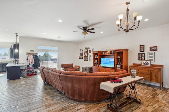 living room featuring ceiling fan with notable chandelier and light hardwood / wood-style flooring