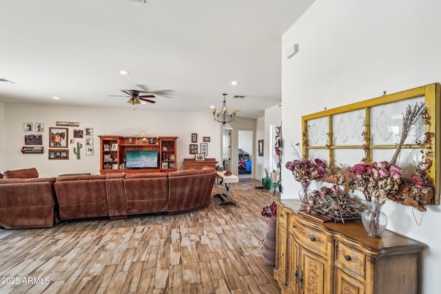 living room with ceiling fan with notable chandelier and light wood-type flooring