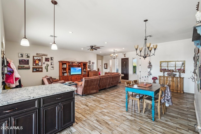 dining room with ceiling fan with notable chandelier and light hardwood / wood-style flooring