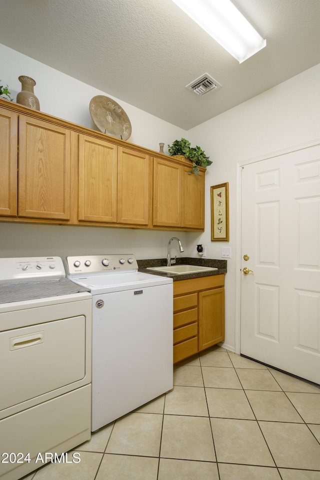 clothes washing area with washer and dryer, cabinets, light tile patterned floors, and sink