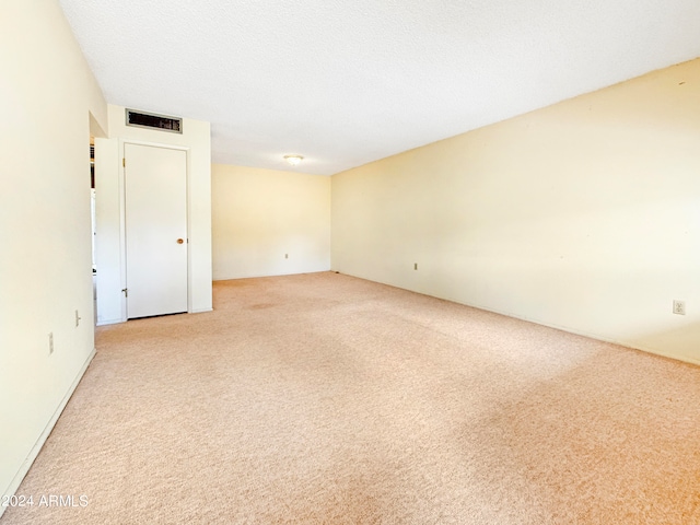 spare room with a textured ceiling and light colored carpet