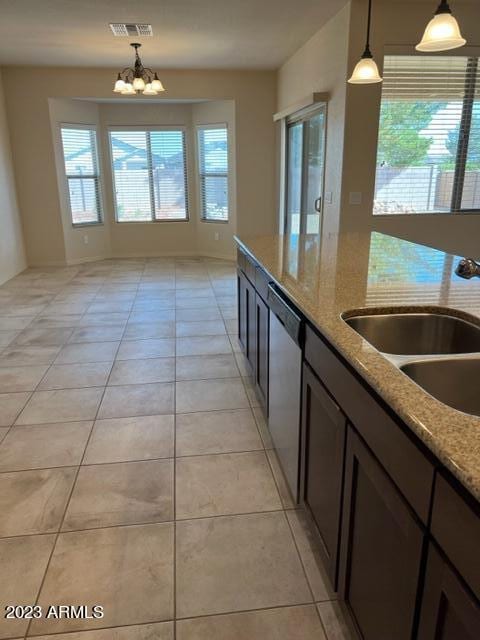 kitchen featuring light stone countertops, stainless steel dishwasher, sink, a notable chandelier, and hanging light fixtures