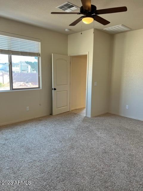 empty room featuring ceiling fan and light carpet