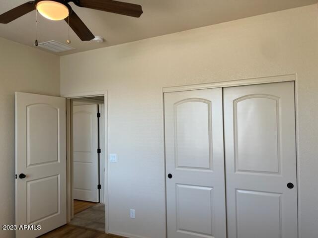 unfurnished bedroom with ceiling fan, dark hardwood / wood-style floors, and a closet