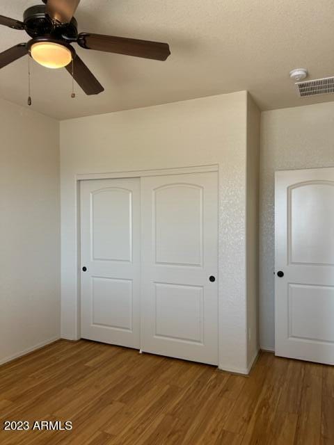 unfurnished bedroom featuring ceiling fan, a closet, and hardwood / wood-style flooring