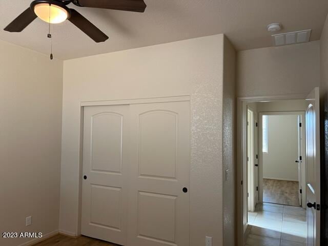 unfurnished bedroom with ceiling fan and a closet