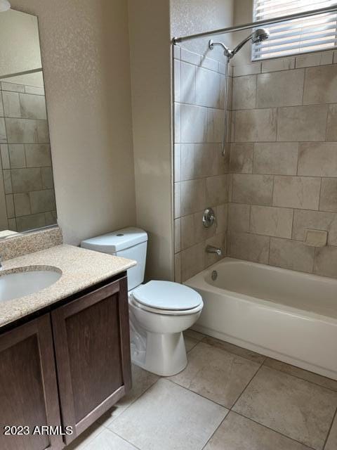 full bathroom with tile patterned flooring, vanity, tiled shower / bath combo, and toilet