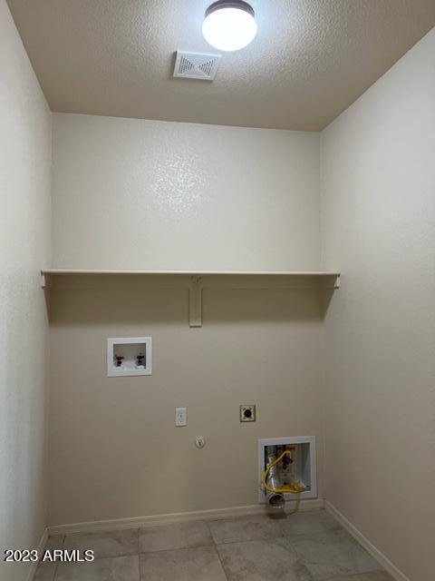 laundry area with electric dryer hookup, gas dryer hookup, hookup for a washing machine, and a textured ceiling