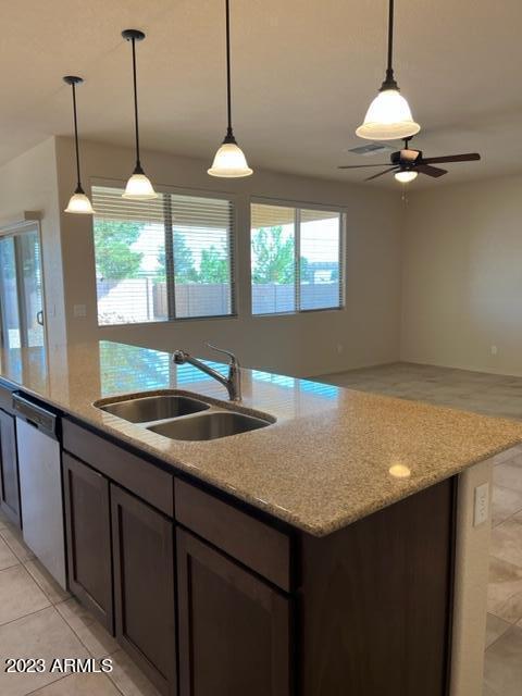 kitchen featuring pendant lighting, light stone countertops, sink, and stainless steel dishwasher