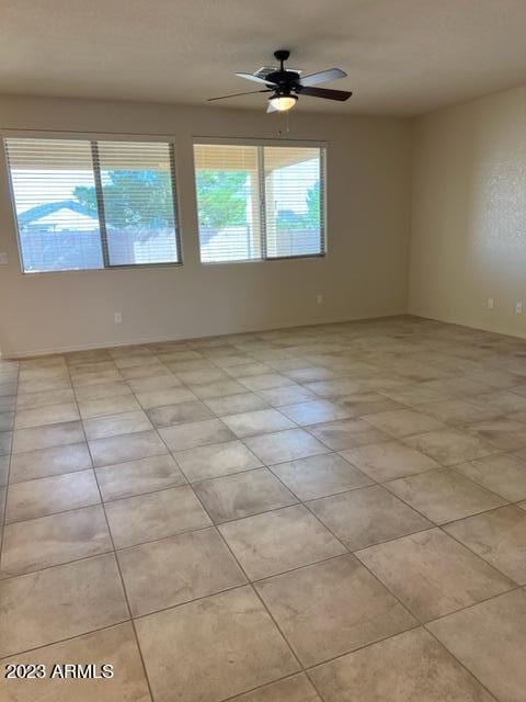 tiled empty room featuring a wealth of natural light and ceiling fan