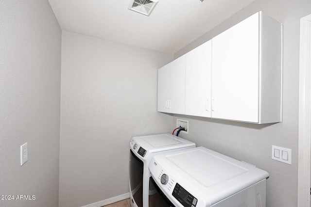 laundry room featuring washing machine and clothes dryer and cabinets