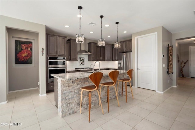 kitchen with appliances with stainless steel finishes, dark brown cabinetry, an island with sink, a kitchen bar, and decorative backsplash