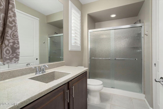 bathroom with vanity, a shower with door, tile patterned floors, and toilet