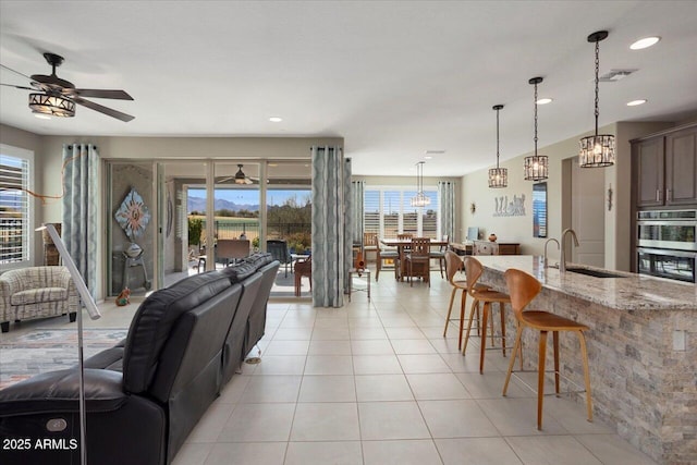 living room featuring sink, light tile patterned floors, and ceiling fan