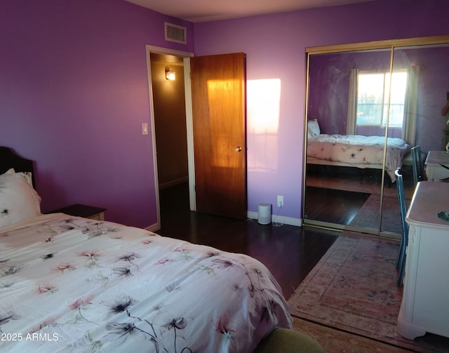 bedroom with baseboards, visible vents, a closet, and wood finished floors