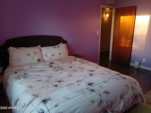 bedroom featuring wood finished floors, visible vents, and baseboards