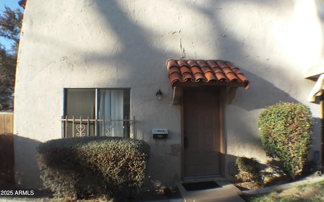 property entrance with a tiled roof and stucco siding