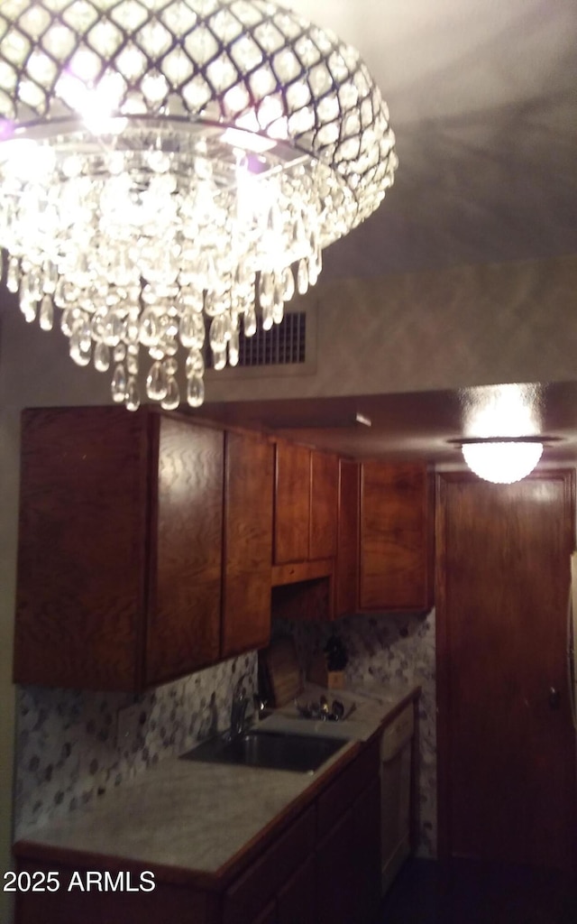 kitchen featuring brown cabinets, light countertops, visible vents, a sink, and dishwasher