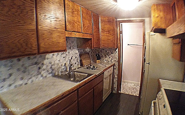 kitchen featuring a sink, brown cabinetry, white dishwasher, and backsplash