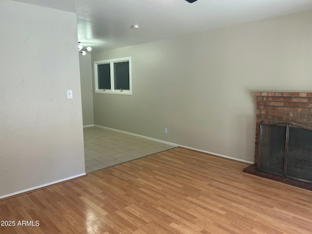 unfurnished living room with a brick fireplace and light hardwood / wood-style flooring