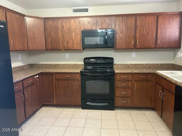 kitchen featuring sink, light tile patterned floors, and black appliances