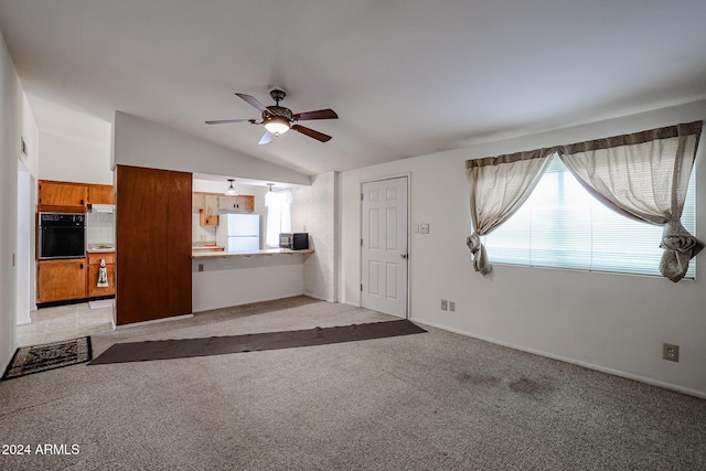 unfurnished living room with ceiling fan, light colored carpet, and vaulted ceiling