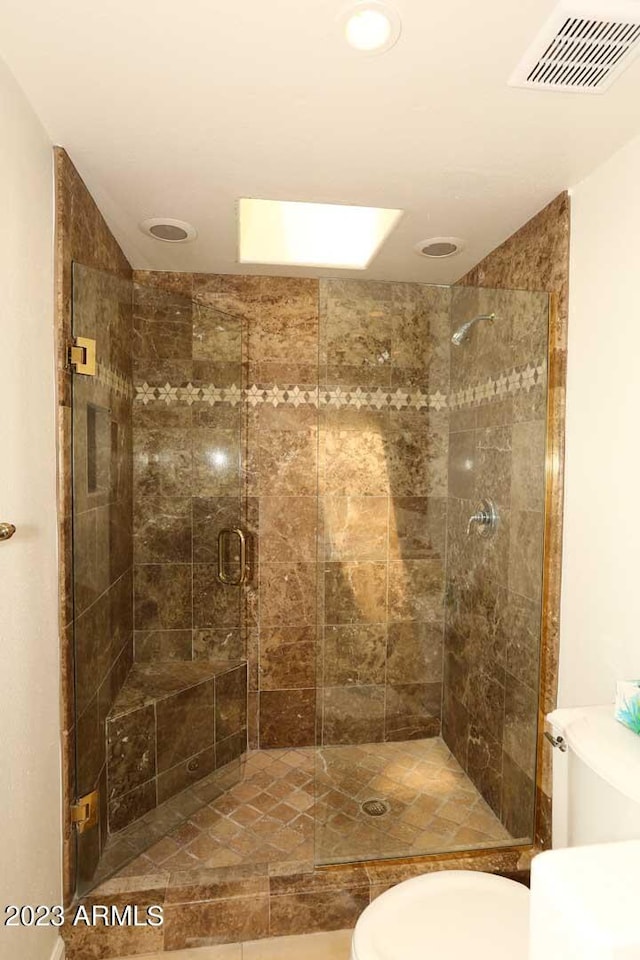 bathroom featuring a shower with door and toilet