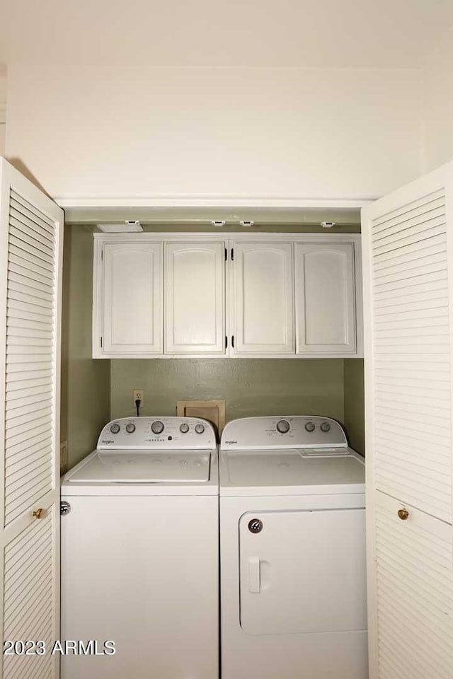 clothes washing area with cabinets and washing machine and dryer