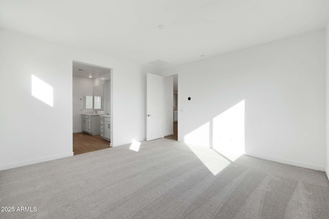 unfurnished bedroom featuring ensuite bath and light colored carpet