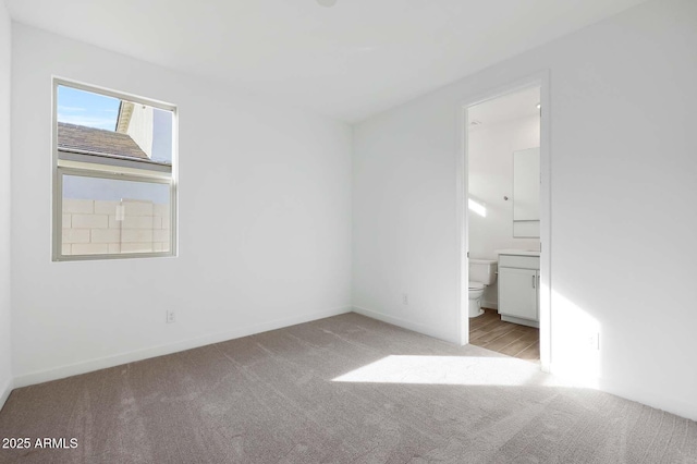 unfurnished bedroom with ensuite bath and light colored carpet