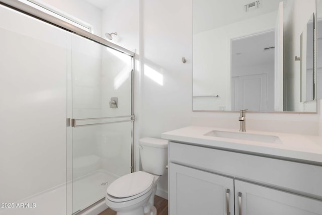 bathroom featuring vanity, an enclosed shower, and toilet