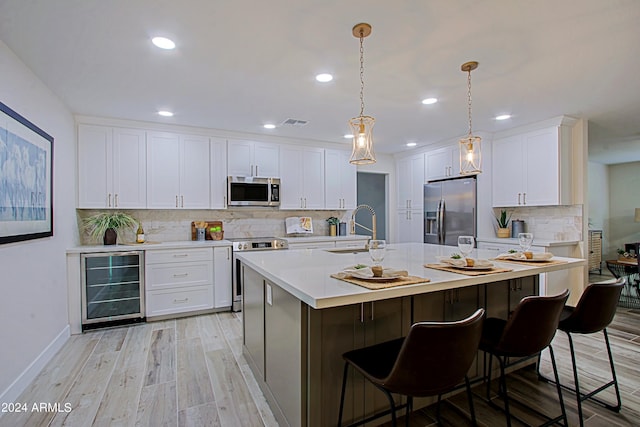 kitchen featuring hanging light fixtures, wine cooler, sink, appliances with stainless steel finishes, and white cabinetry