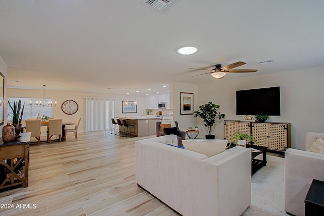 living room featuring light wood-type flooring and ceiling fan with notable chandelier