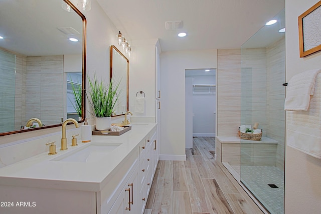 bathroom with hardwood / wood-style flooring, vanity, and a tile shower