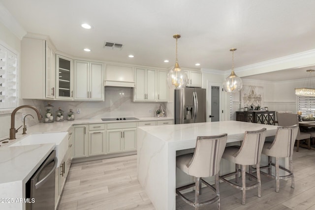 kitchen with a sink, custom range hood, visible vents, a kitchen island, and appliances with stainless steel finishes