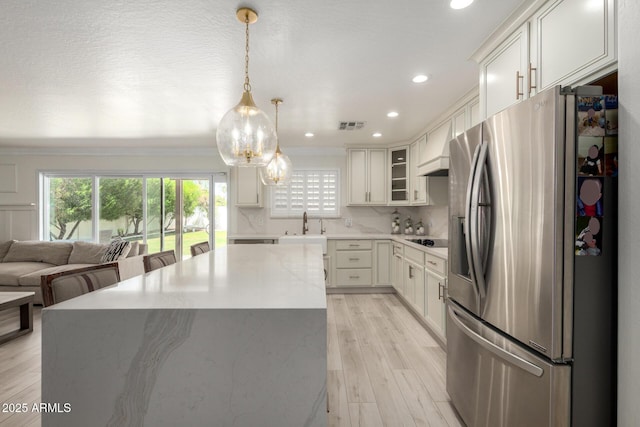 kitchen with black electric cooktop, stainless steel fridge, a center island, and plenty of natural light