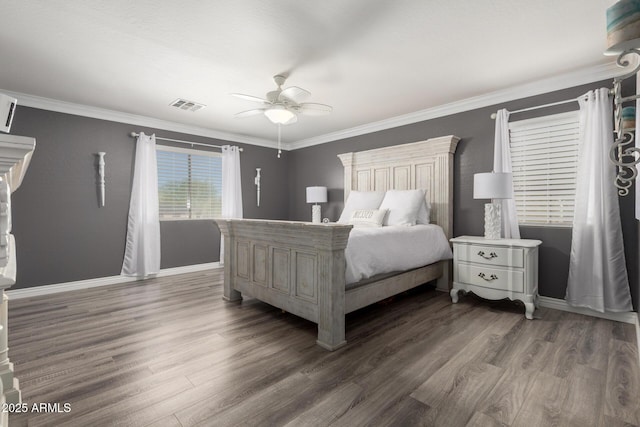 bedroom with wood finished floors, visible vents, crown molding, and baseboards