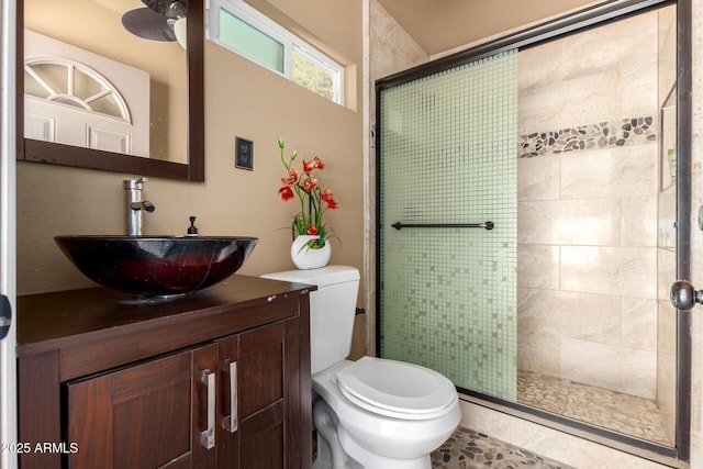 bathroom with toilet, a ceiling fan, a shower stall, and vanity