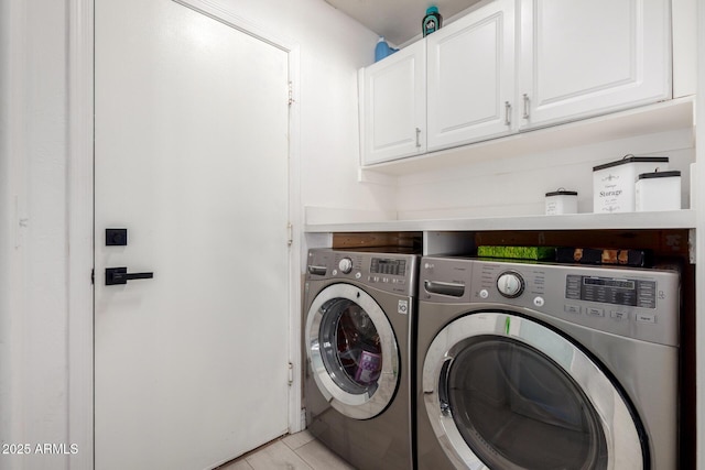 washroom with light tile patterned floors, cabinet space, and washer and clothes dryer